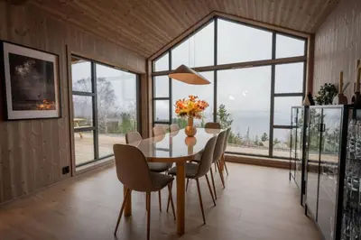 a dining room with a table and chairs and windows at Luxury cabin, Wellness and view over the Tyrifjord in Vikersund