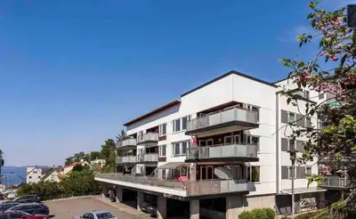 a white building with balconies and a parking lot at Newly renovated 3-room apartment in Bergen