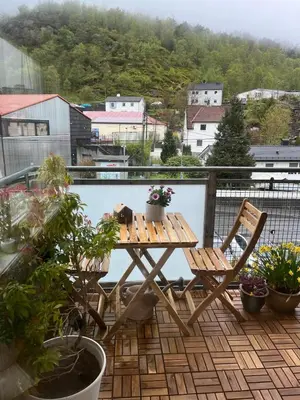 a wooden table and chairs on a balcony with plants at Newly renovated 3-room apartment in Bergen