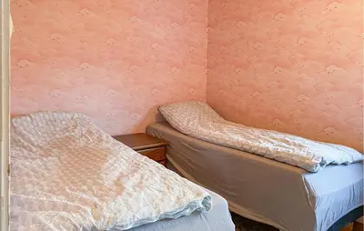 two beds in a room with a wall at Nice Home In Harøya With Harbor View in Steinshamn