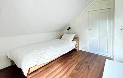a white bed in a room with a wooden floor at Cozy Home In Stongfjorden With House Sea View in Stongfjorden