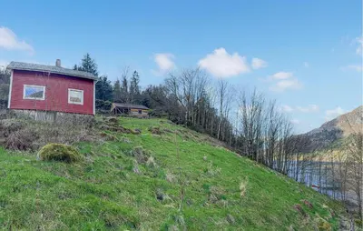 a red house on top of a grassy hill at Cozy Home In Stongfjorden With House Sea View in Stongfjorden