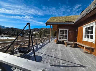 a wooden deck with a hammock on a house at Family-friendly cabin at Høgevarde! in Flå