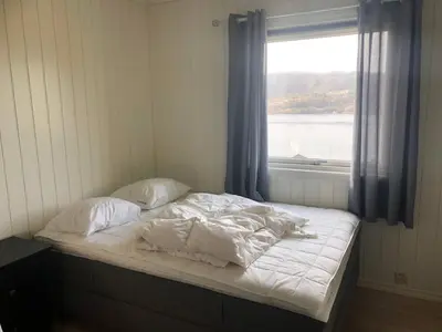an unmade bed in a room with a window at House with oceanview, 4 bedrooms, close to Bergen in Alversund