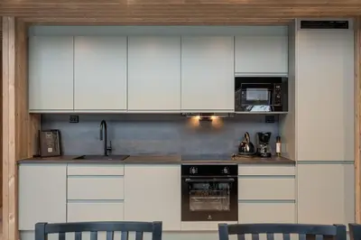 a kitchen with white cabinets and a sink and chairs at Vestbyvegen 34A By Vacation Trysil in Trysil