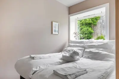 a bed with white sheets in a room with a window at Cozy Apartment in Bergen in Bergen