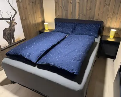 a bed with a blue comforter in a bedroom at Gemütliche Hütte in traumhafter Natur auf 1000 m in Ål