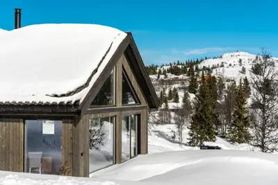 a cabin covered in snow with a mountain in the background at Gemütliche Hütte in traumhafter Natur auf 1000 m in Ål