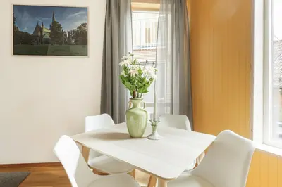 a white table with white chairs and a vase with flowers at Stylish apt 2nd floor city centre in Trondheim