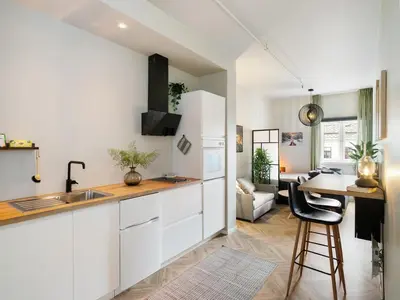 a kitchen with white cabinets and a table in a room at 3FF - Newly renovated studio apt in the middle of the city centre in Trondheim