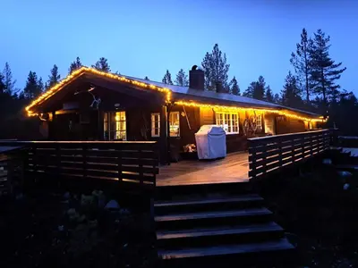 a cabin with lights on the deck at night at 8 person holiday home in Jordet in Jordet