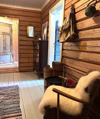 a living room with a wooden wall and a chair at Charming Guesthouse farm in Hølera