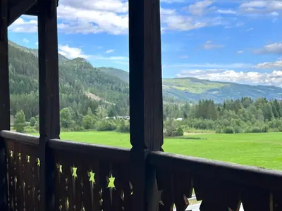 a view from a balcony of a green field and mountains at Charming Guesthouse farm in Hølera