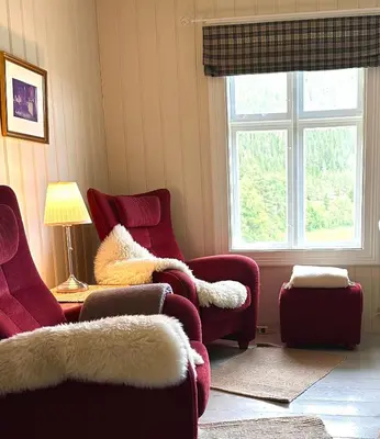 a living room with two chairs and a window at Charming Guesthouse farm in Hølera