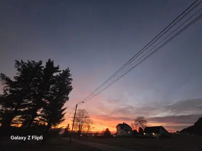 a sunset with power lines in front of a house at Apartament Vigra Fjord in Synes