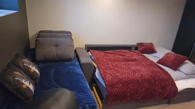 a bedroom with a bed and a couch with a blanket at Apartament Vigra Fjord in Synes