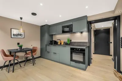 a kitchen with black cabinets and a table and chairs at Grand Junior Suite in Molde