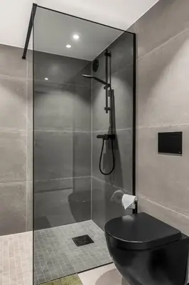 a bathroom with a black toilet and a shower at Grand Junior Suite in Molde