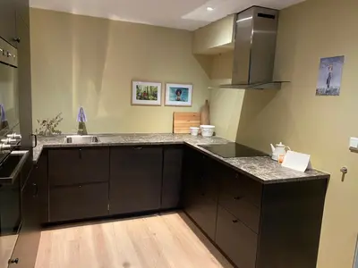 a kitchen with black cabinets and a counter top at Koselig, ny 1-roms hybelleilighet med moderne kjøkken in Stord