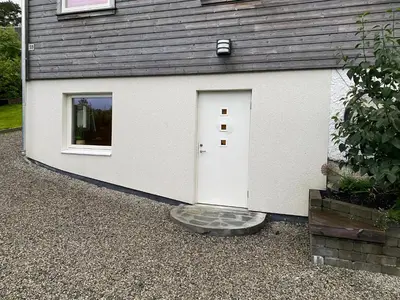 a white garage with a door and a window at Koselig, ny 1-roms hybelleilighet med moderne kjøkken in Stord