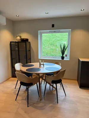 a dining room with a table and chairs and a window at Nyoppusset leilighet til leie in Isfjorden