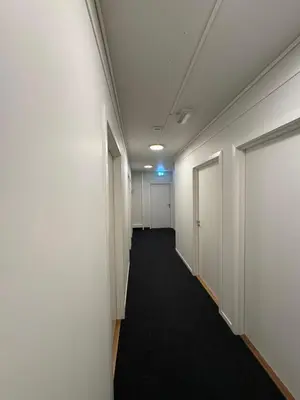 a hallway of an office with white walls and a black carpet at Siggjo Guesthouse Bømlo and Stord in Mosterhamn