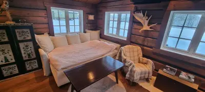 a bedroom with a bed and a table and windows at Krøderen Laftet tømmerstue fra 2021