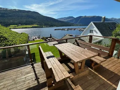 a wooden deck with a picnic table and a view of a lake at 4 star holiday home in Eidsvåg in Eidsvåg