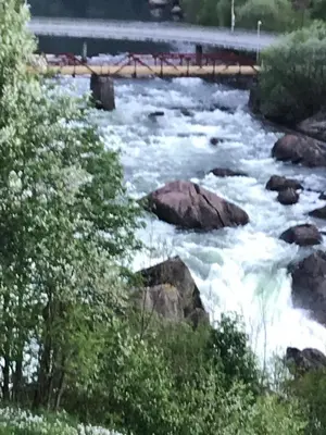a river with rapids and rocks and a bridge at Near Trolltunga and centre of Odda in Odda