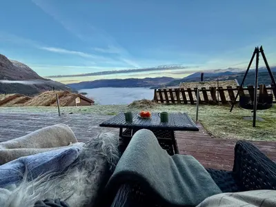 a table and a couch on a deck with a view at Unique view! Modern apartment with sauna in Vossevangen
