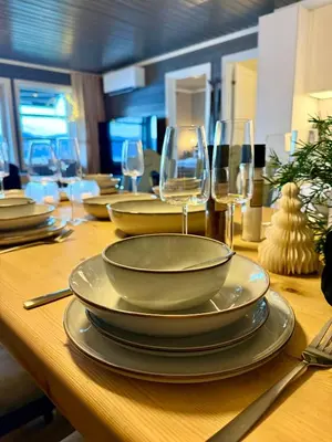 a wooden table with plates and wine glasses on it at Unique view! Modern apartment with sauna in Vossevangen