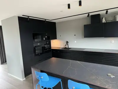 a kitchen with black cabinets and blue chairs at Family-friendly luxury penthhouse with three bedrooms in Stjoerdal