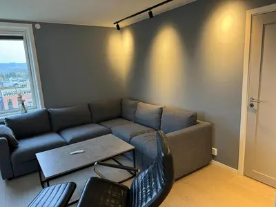 a living room with a couch and a table at Family-friendly luxury penthhouse with three bedrooms in Stjoerdal