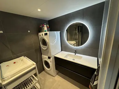 a bathroom with a sink and a washing machine at Family-friendly luxury penthhouse with three bedrooms in Stjoerdal
