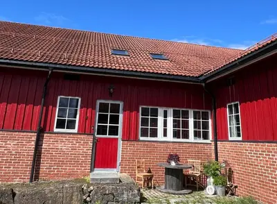 a red brick house with red doors and a table at Leilighet I låve in Gran