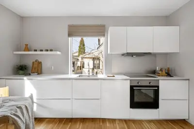 a white kitchen with white cabinets and a window at Cozy 2-bedroom apartment near Bergen City Centre in Bergen