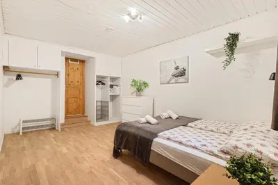 a white bedroom with a bed and a wooden floor at Bergen city center Kalfaveien in Bergen