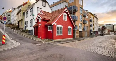 a red house on the side of a city street at Sentralt,unikt lite bergenshus med sjel på fine Nøstet! in Bergen
