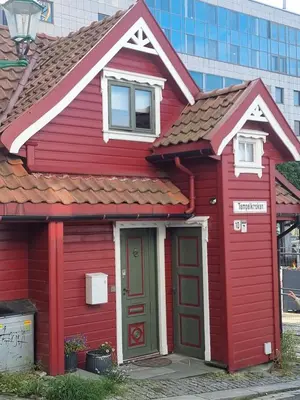 a red house with a red door on a street at Sentralt,unikt lite bergenshus med sjel på fine Nøstet! in Bergen
