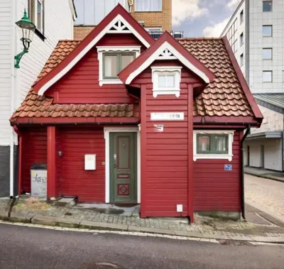 a red house with a red roof on a street at Sentralt,unikt lite bergenshus med sjel på fine Nøstet! in Bergen