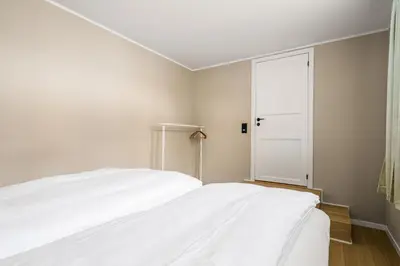 a bedroom with a white bed and a door at Bright & Stylish Apartment in City Center in Bergen