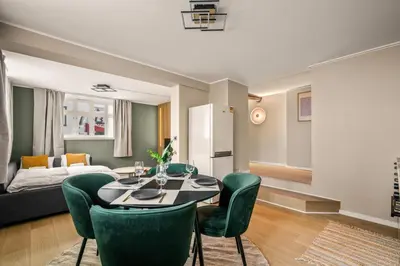 a living room with a table and green chairs at Bright & Stylish Apartment in City Center in Bergen