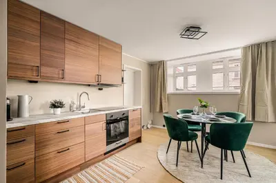 a kitchen with a table and green chairs in a kitchen at Bright & Stylish Apartment in City Center in Bergen