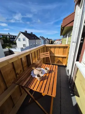 a wooden bench on a balcony with a table at Your home in Kristiansund in Kristiansund