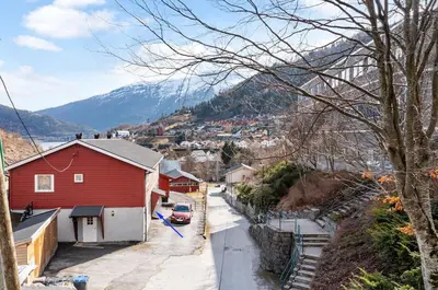 a red house with a red car parked on a street at Tasteful apartment in Sogndal with parking in Sogndal