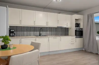 a kitchen with white cabinets and a table at Apartment in idyllic Kristiansund in Kristiansund