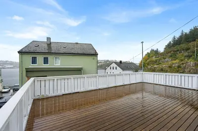a deck with a white fence and a house at Apartment in idyllic Kristiansund in Kristiansund