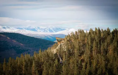 a house on top of a hill with snow covered mountains at Eagle Nest Eco Lodge in Sel
