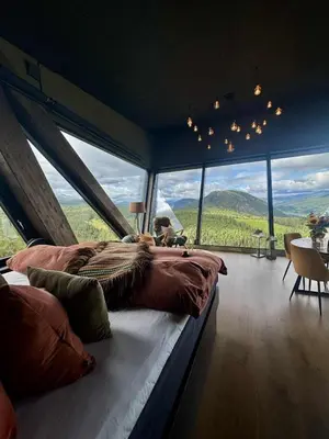 a bedroom with a large bed in a room with large windows at Eagle Nest Eco Lodge in Sel