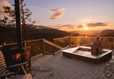 a person sitting in a tub on a deck with a fireplace at Eagle Nest Eco Lodge in Sel